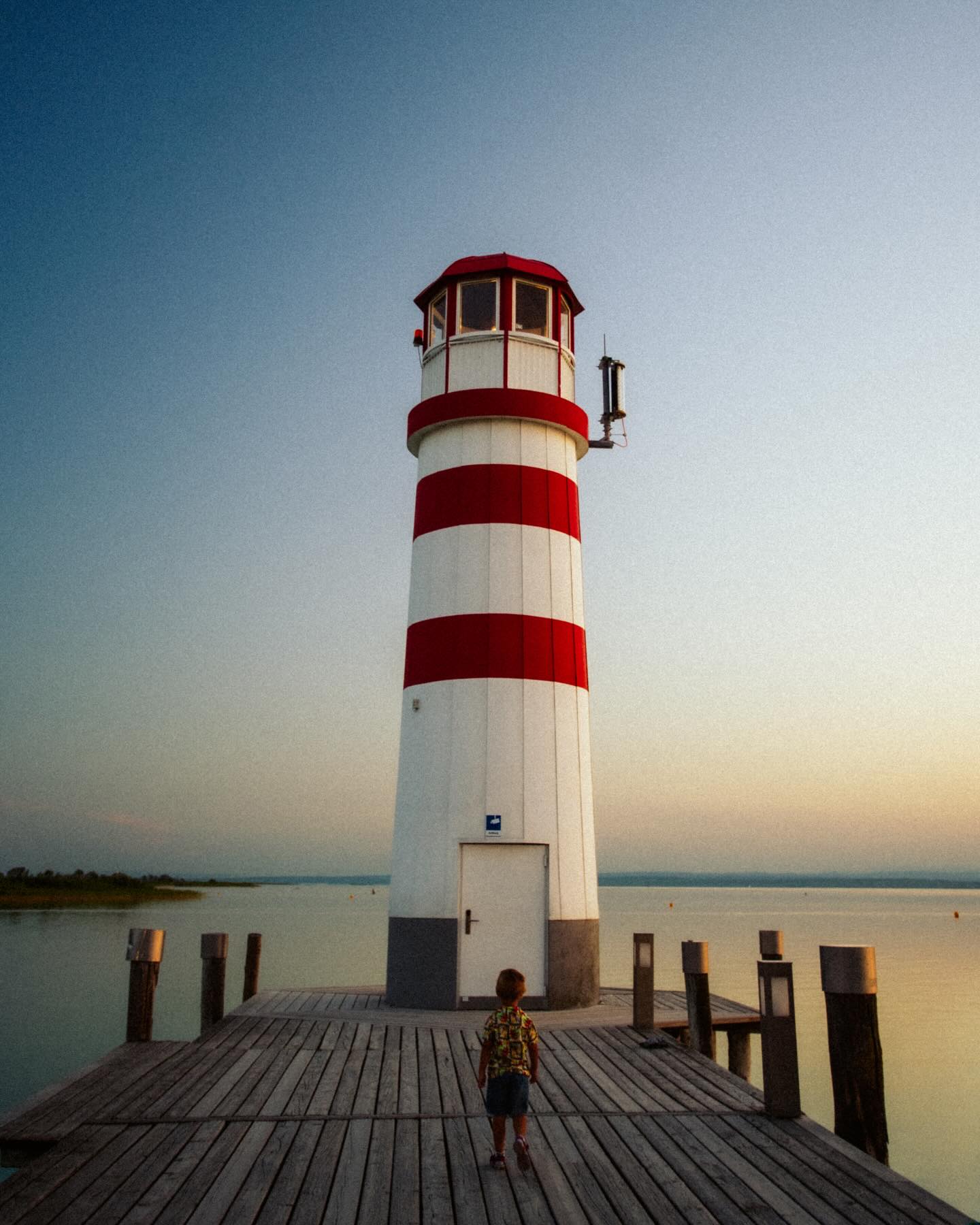 A striped lighthouse beside the water, photographed by Viktor Vilyus